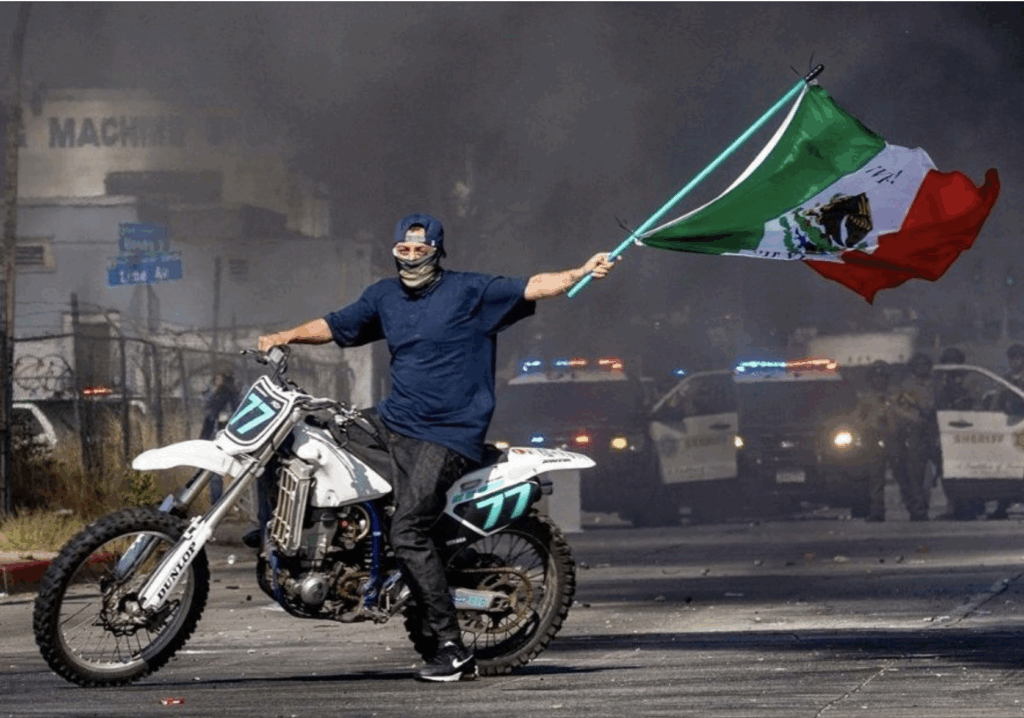 Motociclista sostiene la bandera de México en medio de humareda